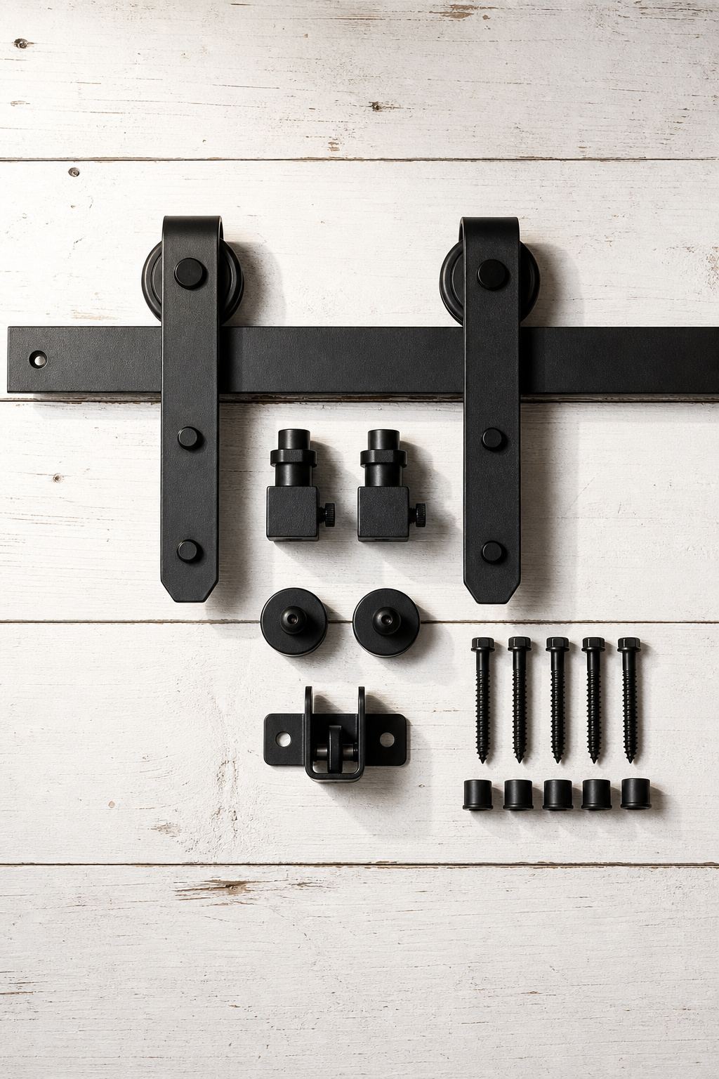 Complete barn door hardware kit components including flat track, J-strap hangers, door stoppers, floor guide and anti-jump discs laid out on a workbench