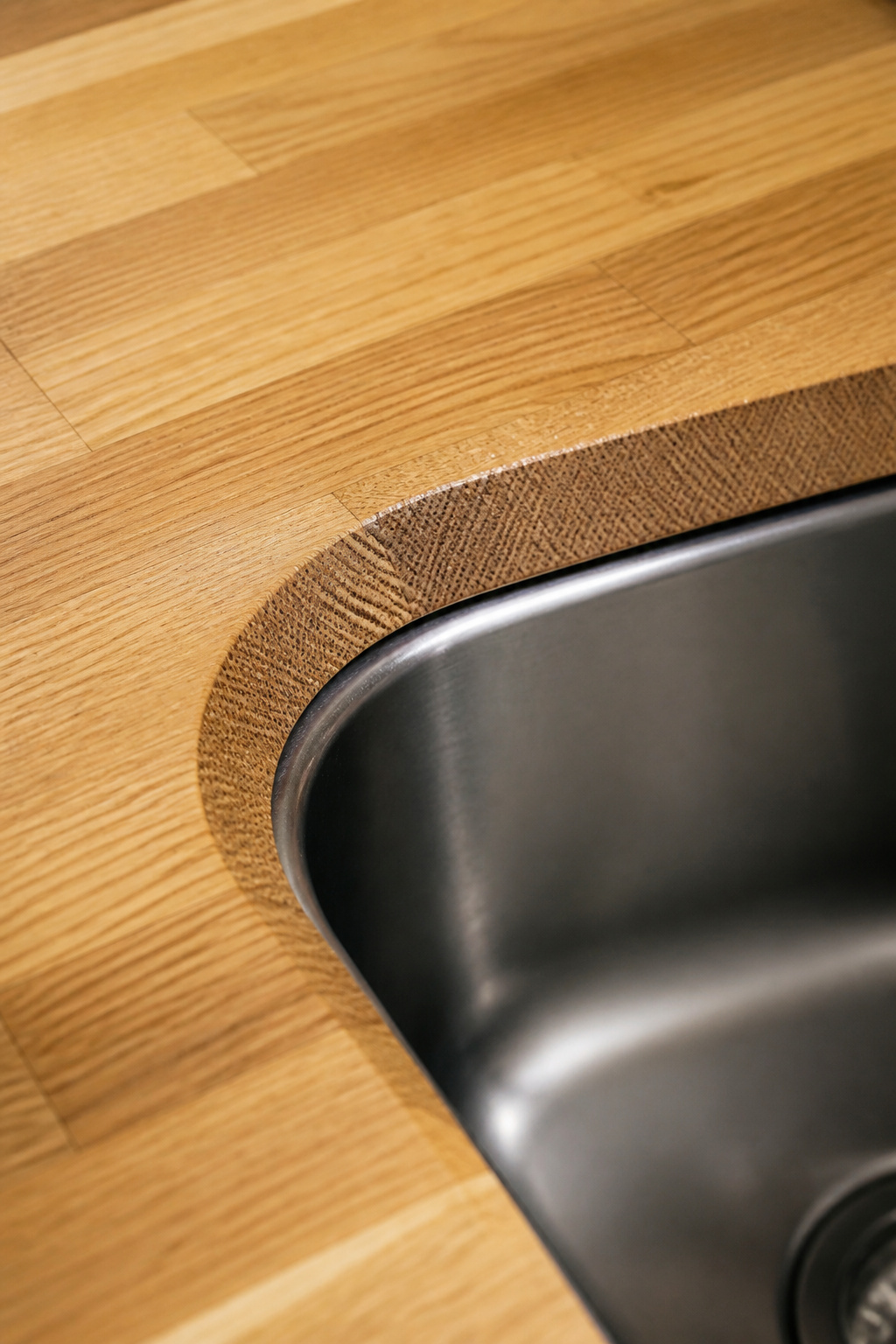 Close-up of exposed end grain at a butcher block sink cutout showing the texture difference from the surface