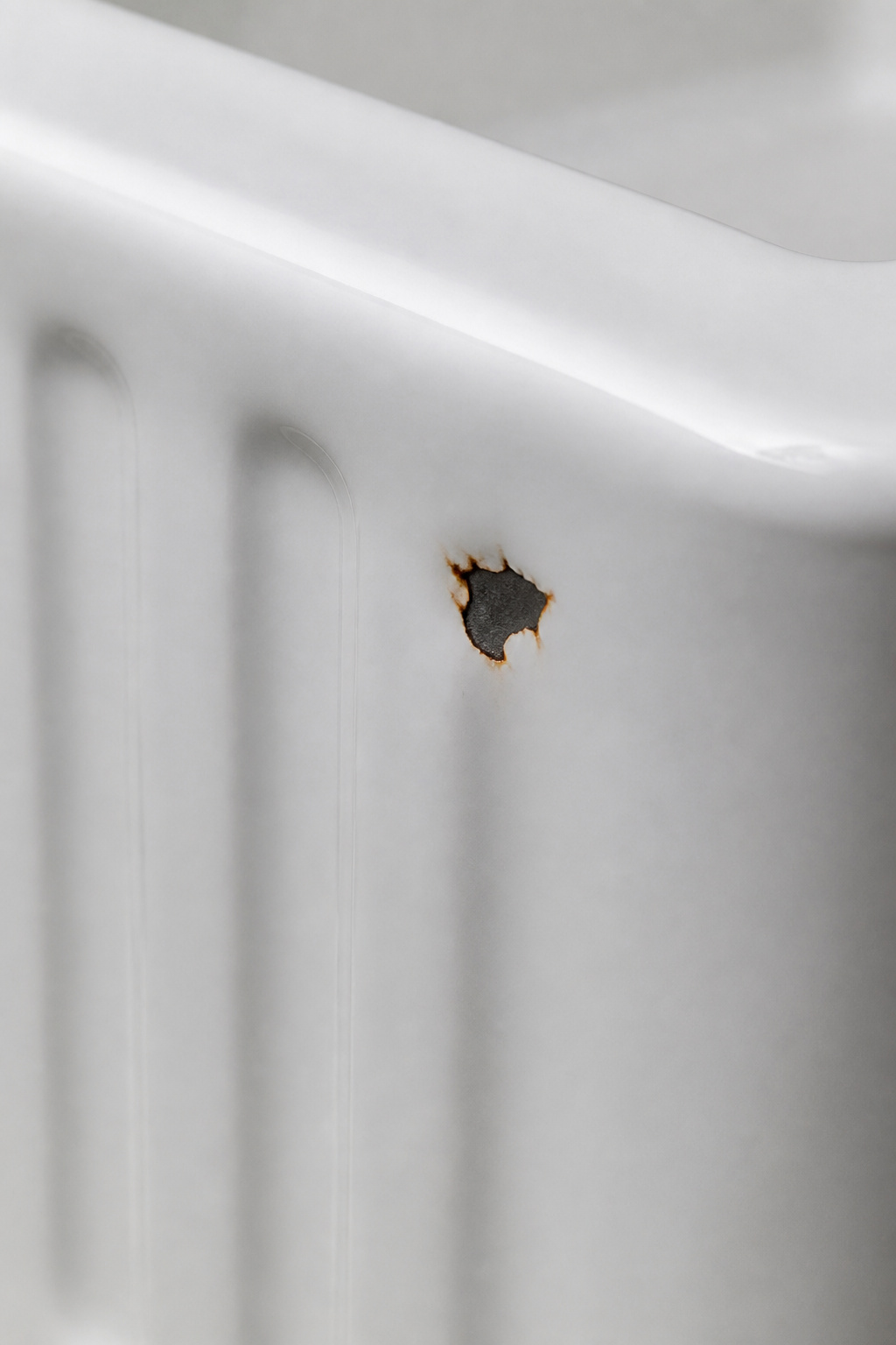 Close-up of cast iron farmhouse sink enamel chip showing rust at the exposed iron beneath