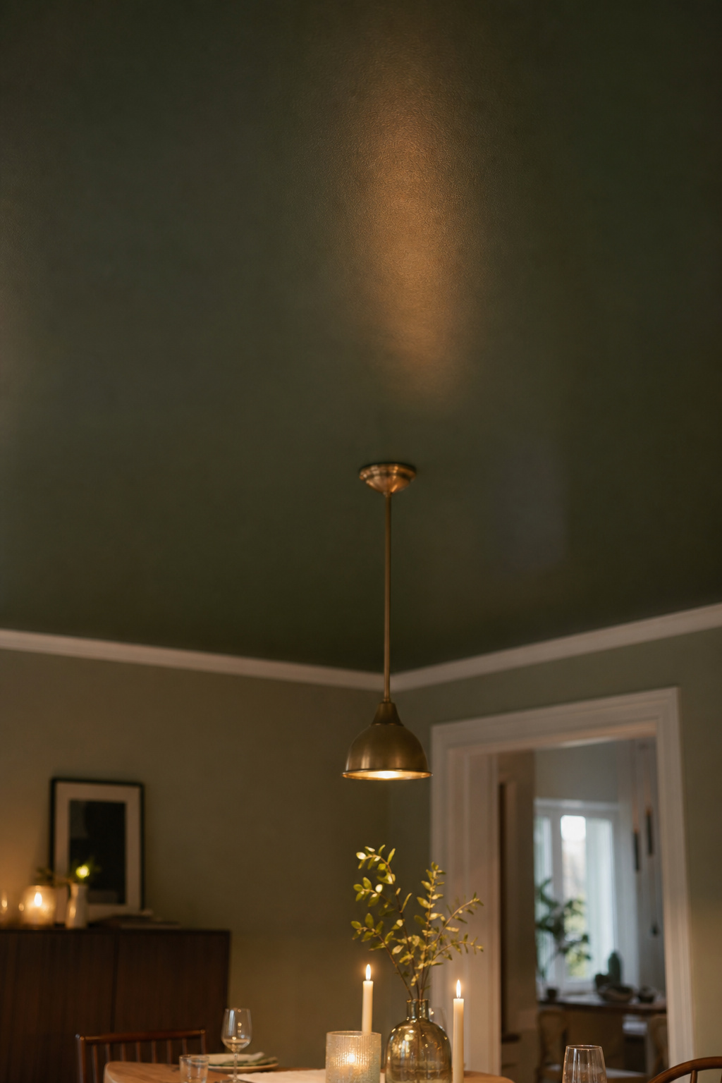 Dining room with deep forest green matte painted ceiling and warm candlelight below
