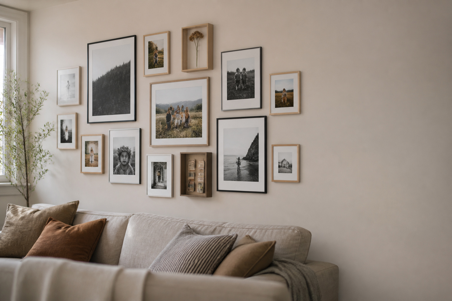 Curated family photo wall in a Scandinavian living room, mixing black and white prints with warm colour photos in oak and black frames, with small shadow box mementos