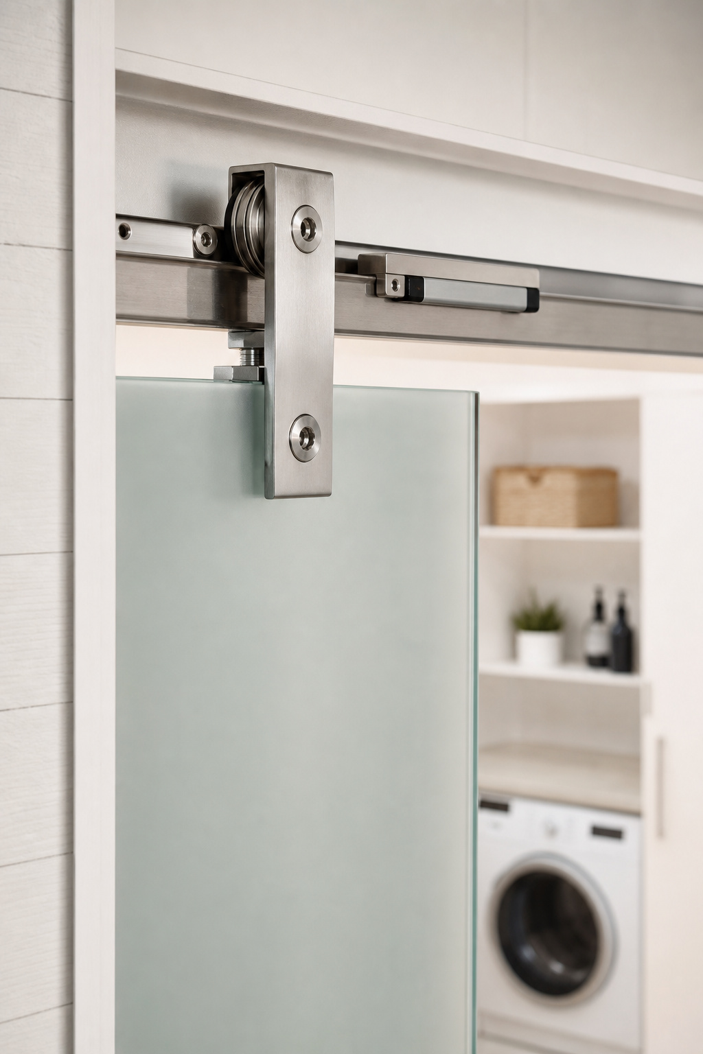 Stainless steel top-mount clamp bracket securing a frosted glass barn door to a flat track, with a soft-close dampener visible along the rail