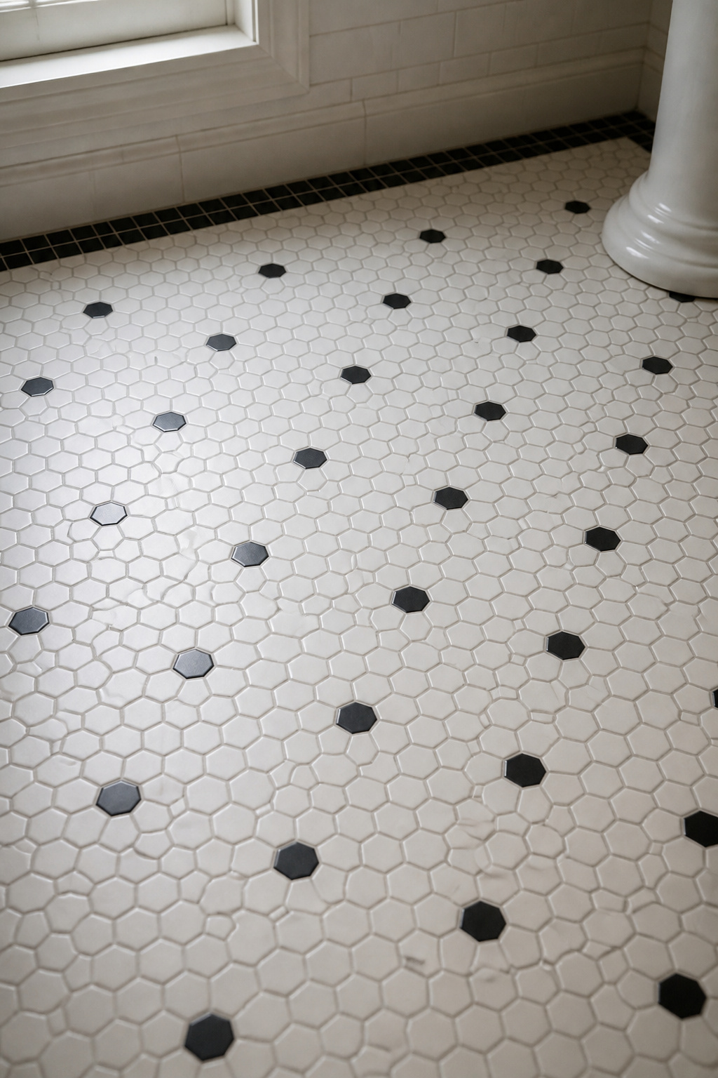 1920s-style bathroom floor with 1-inch white hex tiles, scattered black hex accents, and a black square border, grey grout