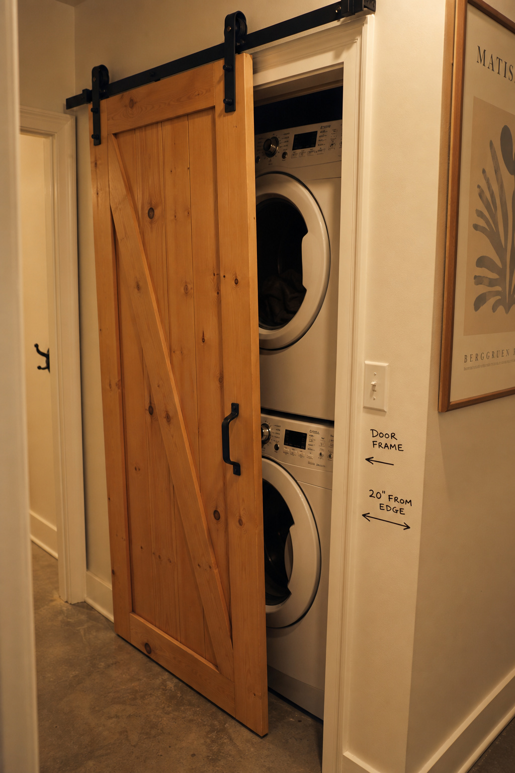 Narrow laundry hallway closet showing a single barn door blocked by a door frame before it can fully clear the opening
