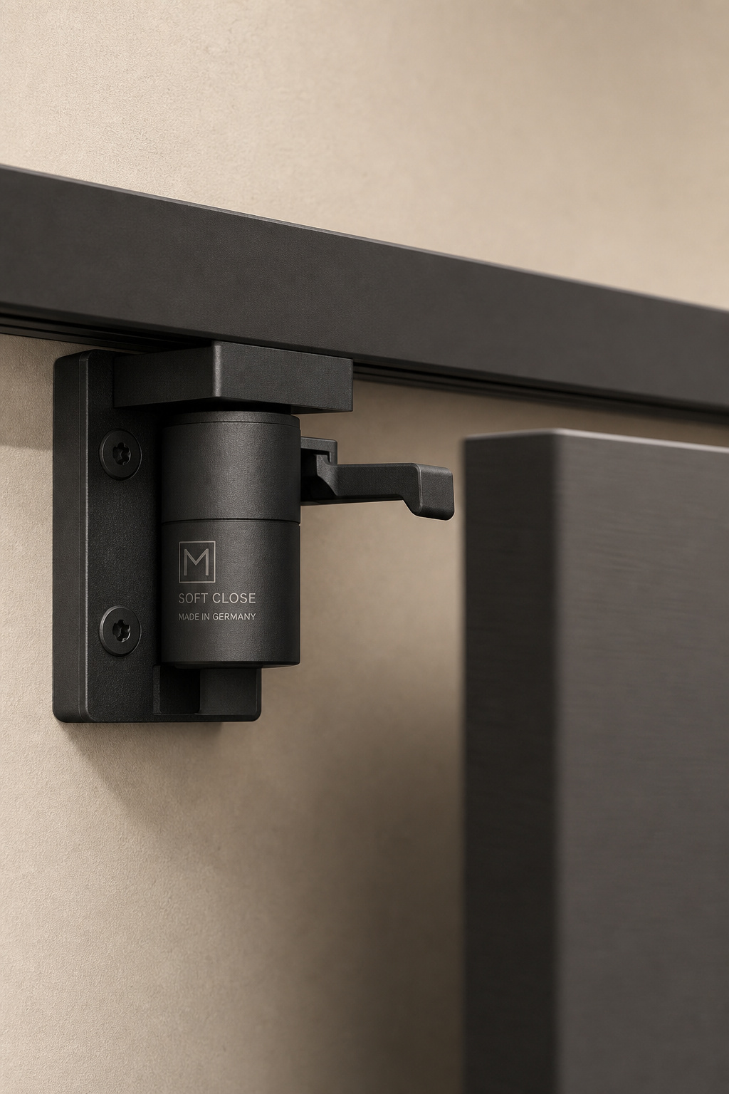 Close-up of a matte-black soft-close barn door mechanism mounted on the end of a flat track, showing the hydraulic damper unit and trigger arm