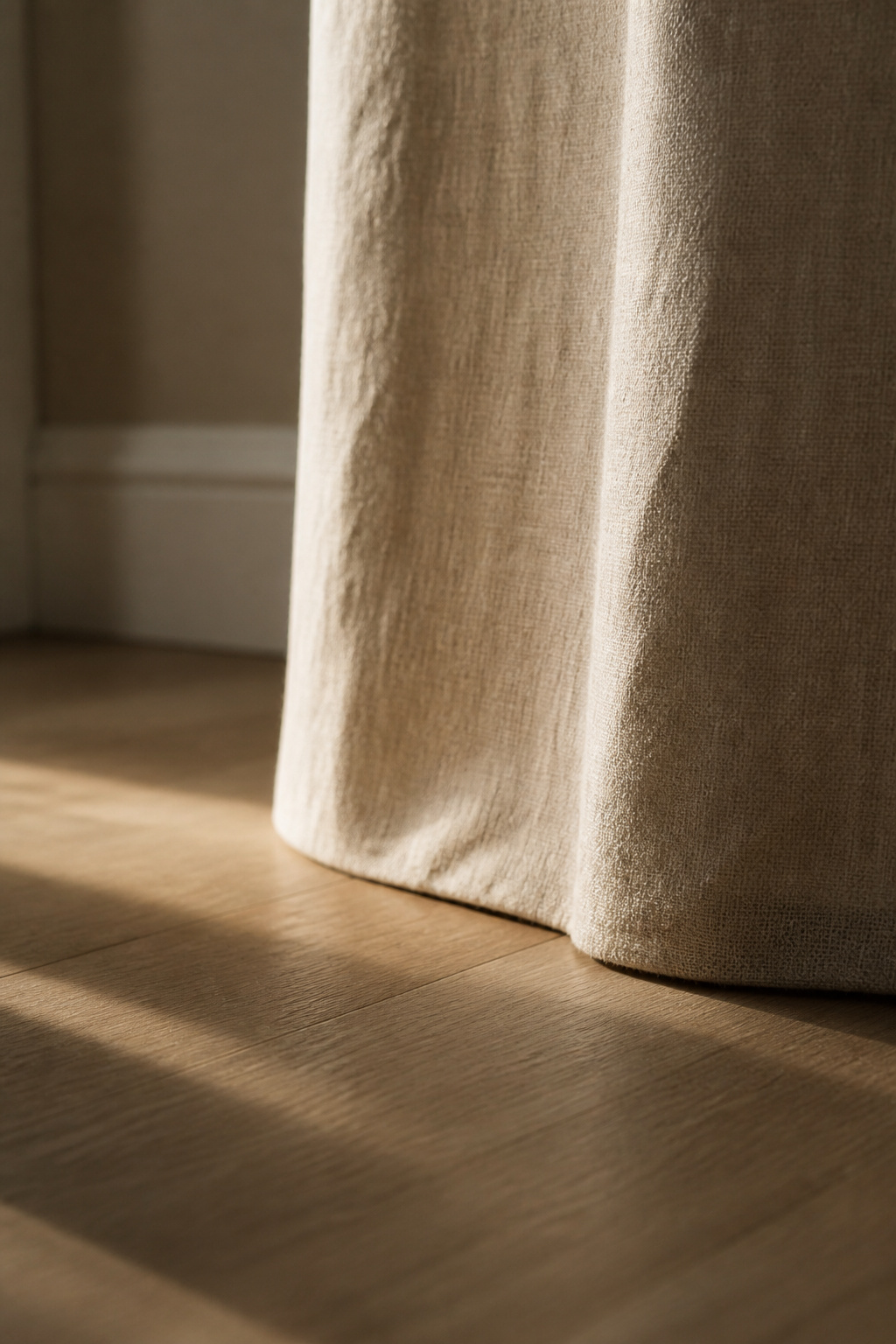 Linen bedroom curtain hem grazing the wood floor in a clean floor-skim finish
