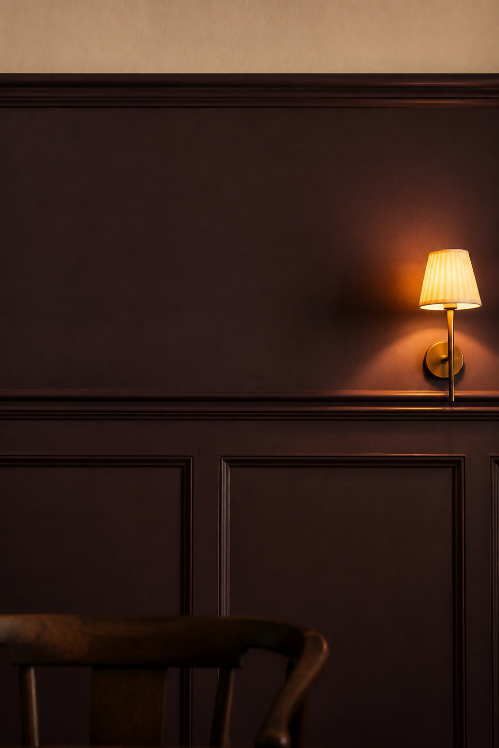 Dining room wainscoting painted in aubergine-plum flat matte, dado rail and panel moulding creating shadow lines against the dark field
