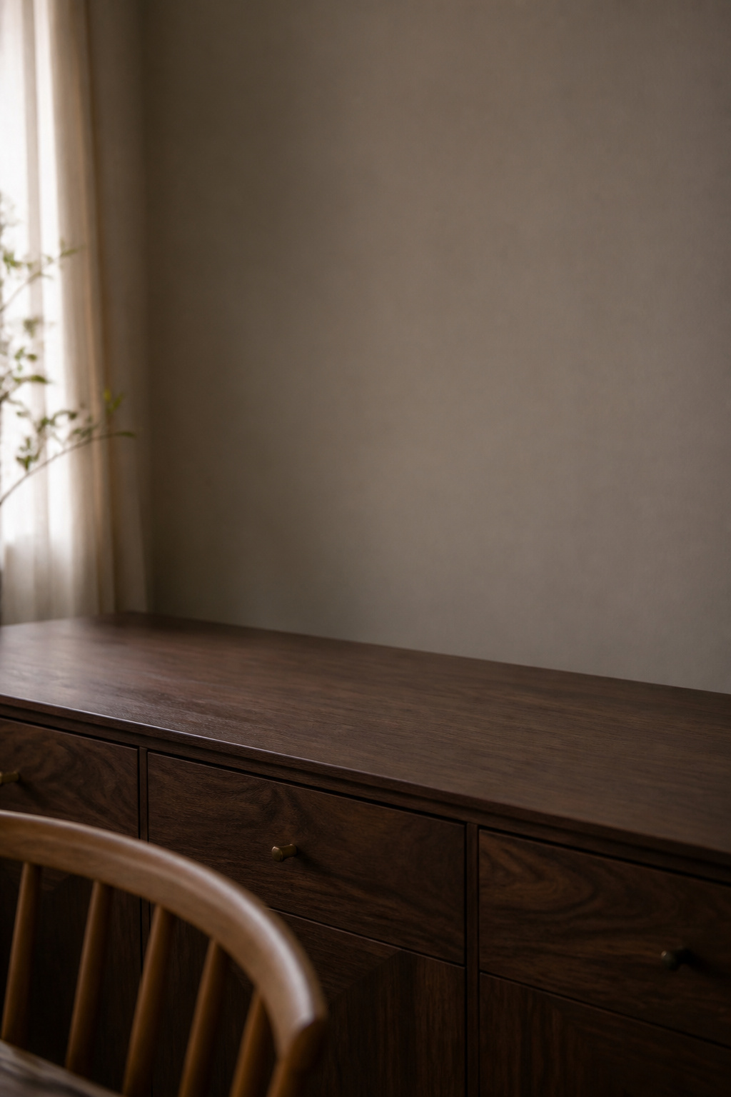 A dark walnut sideboard with a completely clear surface and bare wall above, ready for styling
