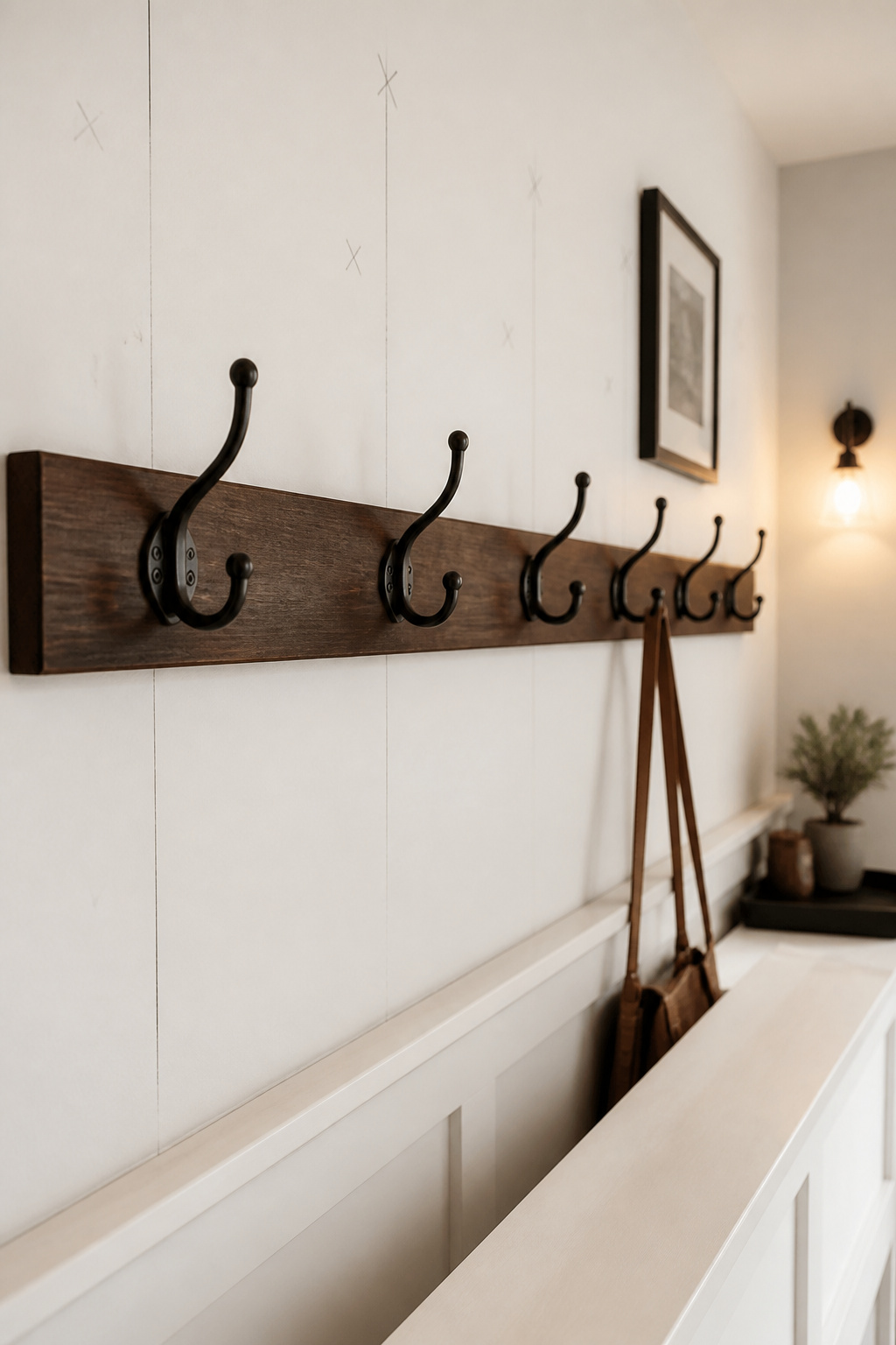 Dark walnut stained poplar hook rail with five oil-rubbed-bronze hooks mounted at 60 inches above a white painted entryway bench
