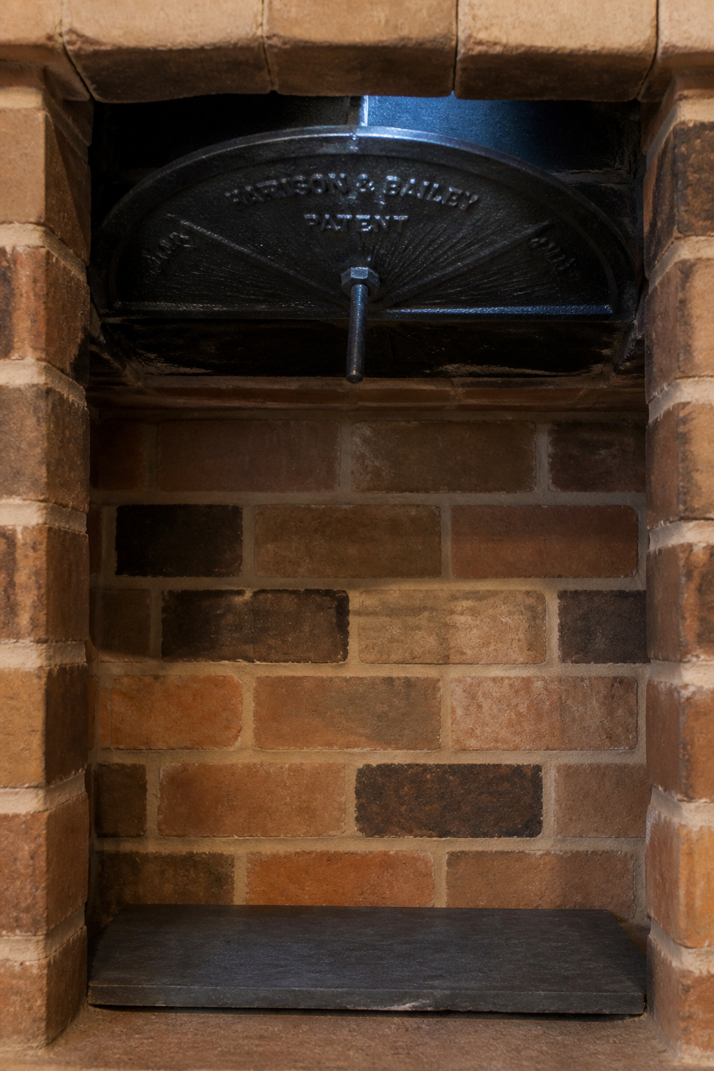 Interior view of a brick firebox showing a half-open cast iron throat damper before styling an unused fireplace