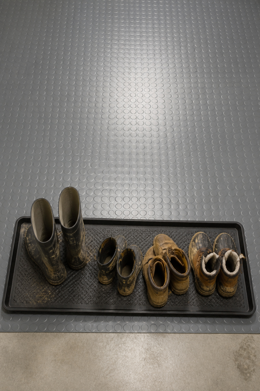 Coin-pattern vinyl garage flooring with a boot tray holding muddy boots, an example of durable garage entry flooring