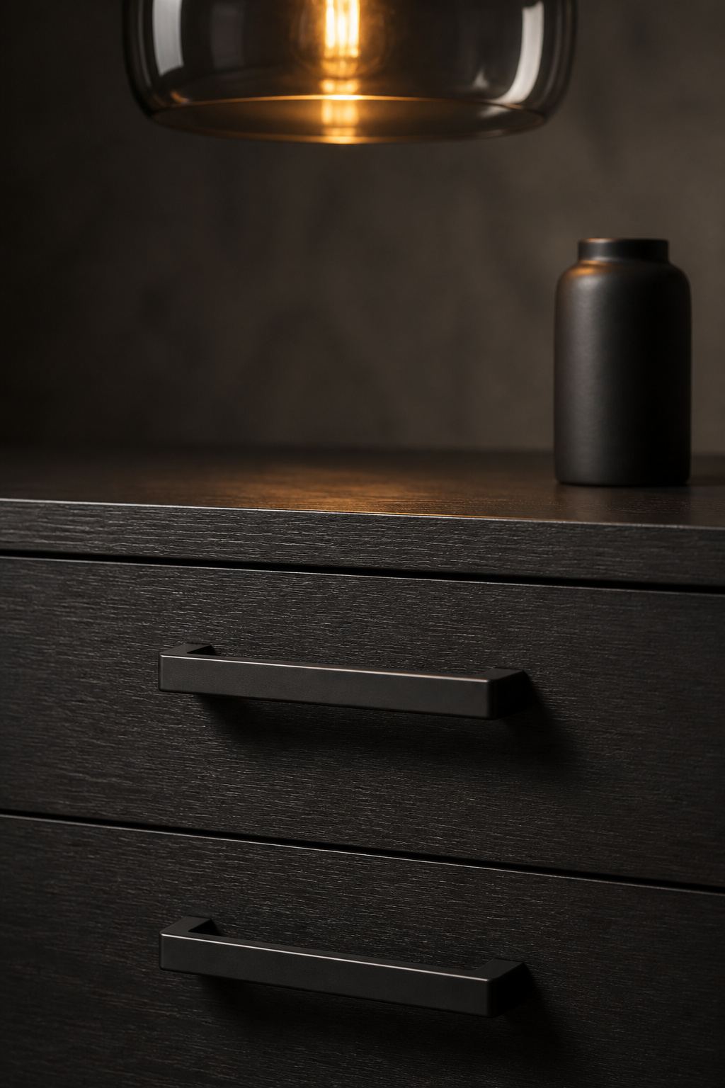 Close-up of slim matte-black bar pulls on charcoal satin credenza drawer with smoked pendant visible above