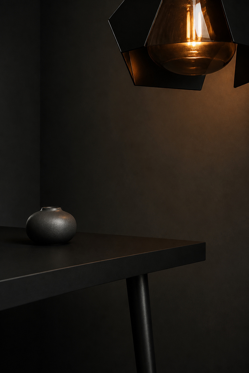 Close-up vignette of matte-black dining table corner with smoked-glass pendant above and warm-graphite wall — modern moody palette