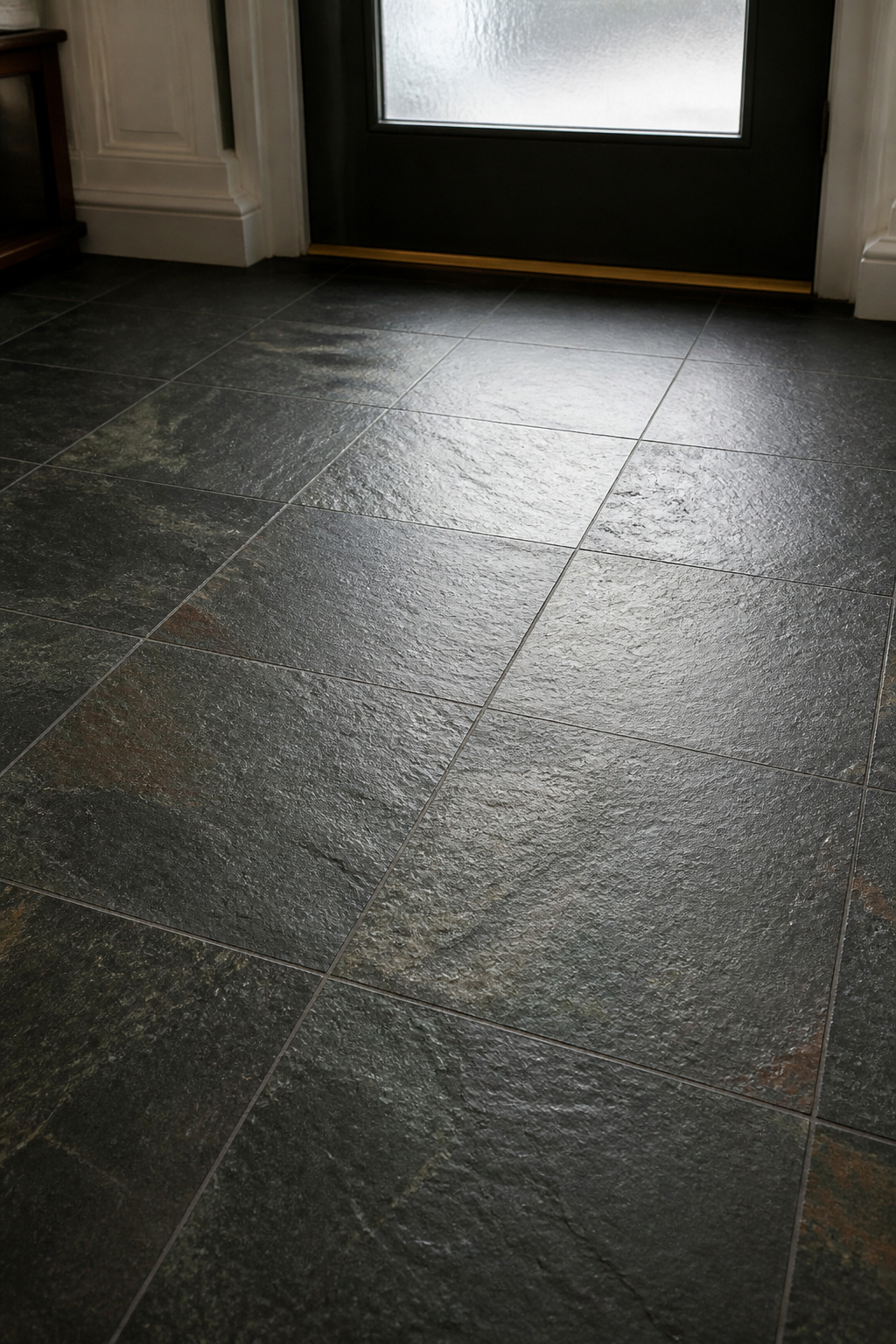 Close-up of natural cleft honed slate floor tiles in dark charcoal-green with riven texture in a formal residential entryway