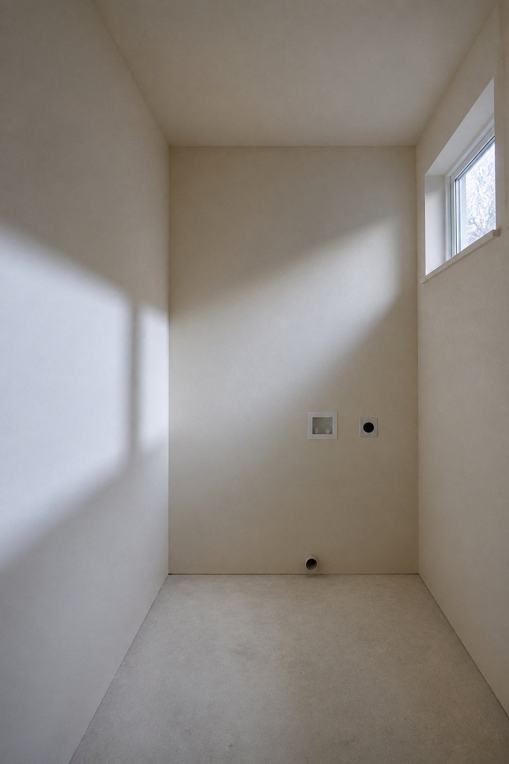 Empty Nordic laundry room with single north-facing window showing how cool winter light shifts warm off-white wall colour