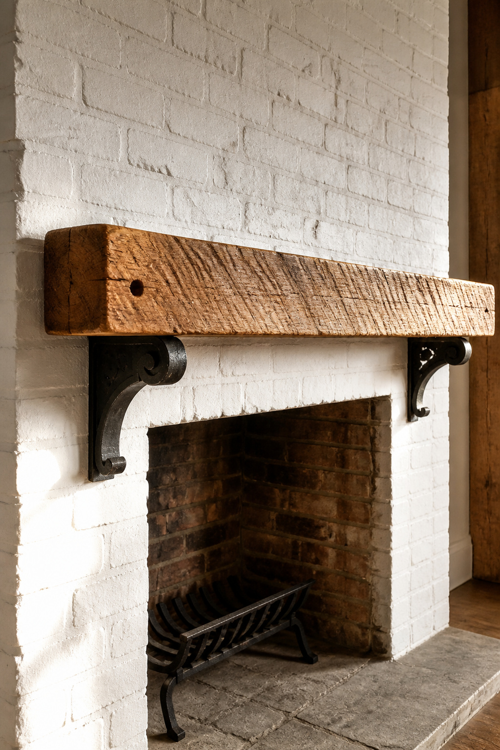 Reclaimed Douglas fir beam mantel resting on aged blackened-iron corbels mounted to a brick chimneybreast, showing original saw marks and honey-amber grain with dark age patina