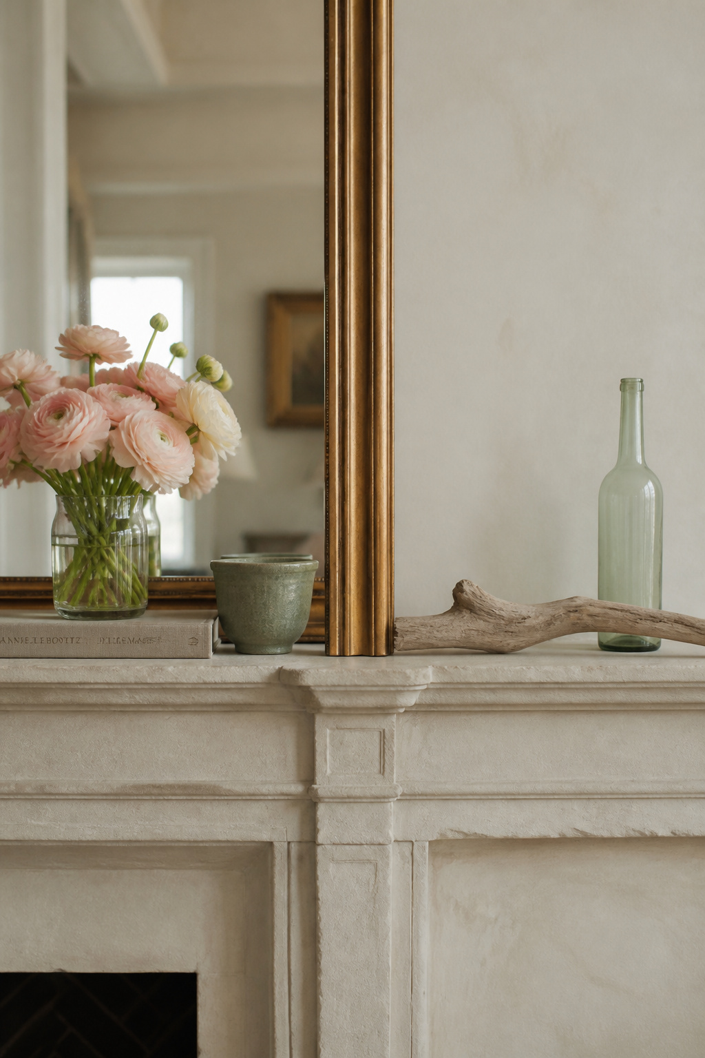 Fireplace mantel split between spring styling with ranunculus and linen and summer styling with driftwood and sea-glass, sharing the same gilt mirror anchor