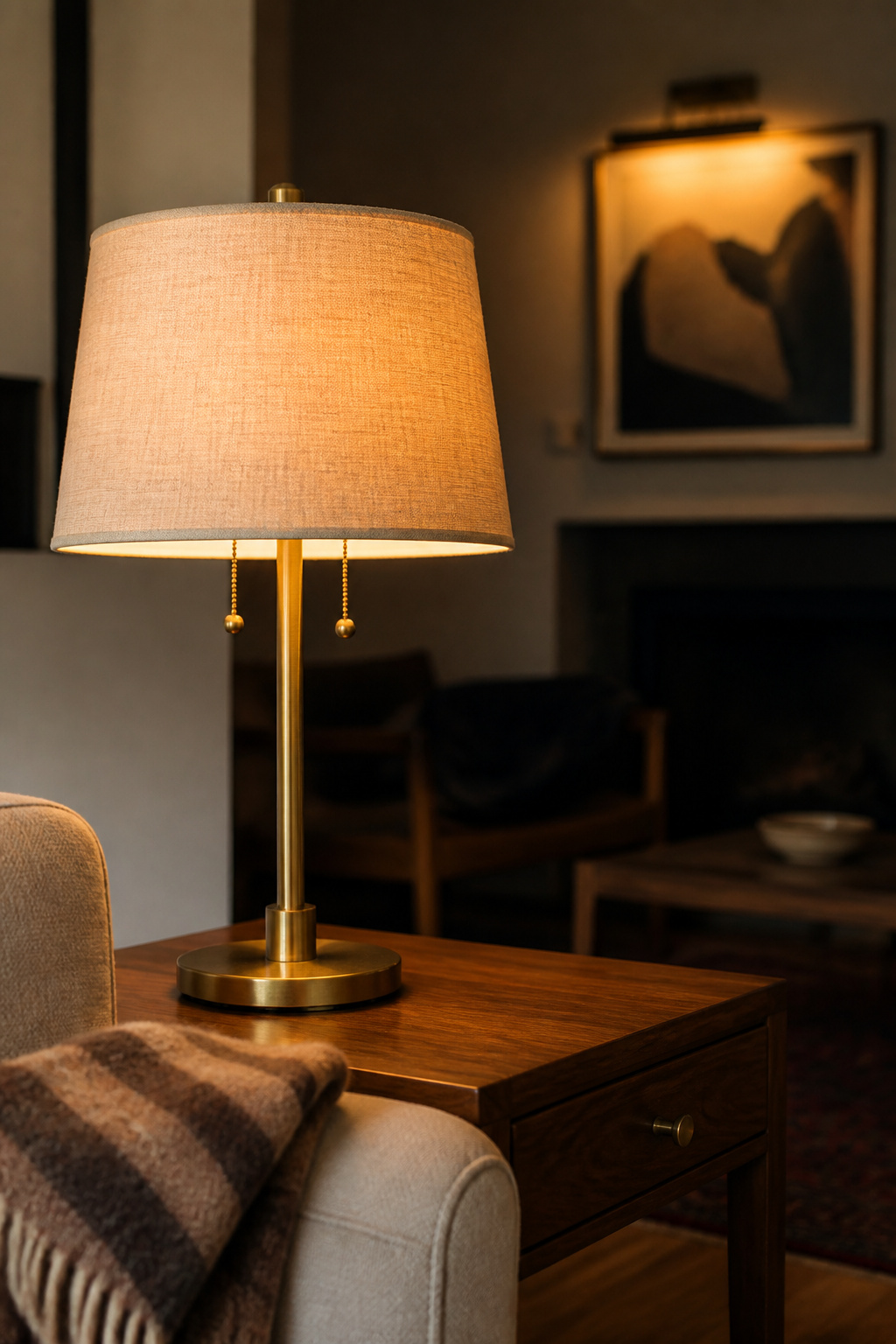 Brass table lamp and wall-washed artwork layering ambient and accent light in a sunken living room pit