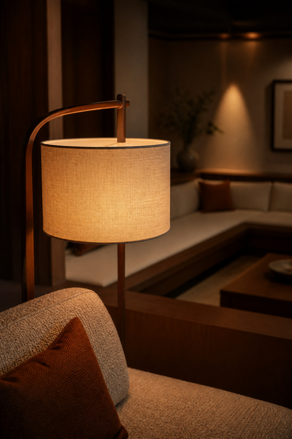 Fabric-shaded floor lamp diffusing light beside sunken living room seating to avoid glare at eye level