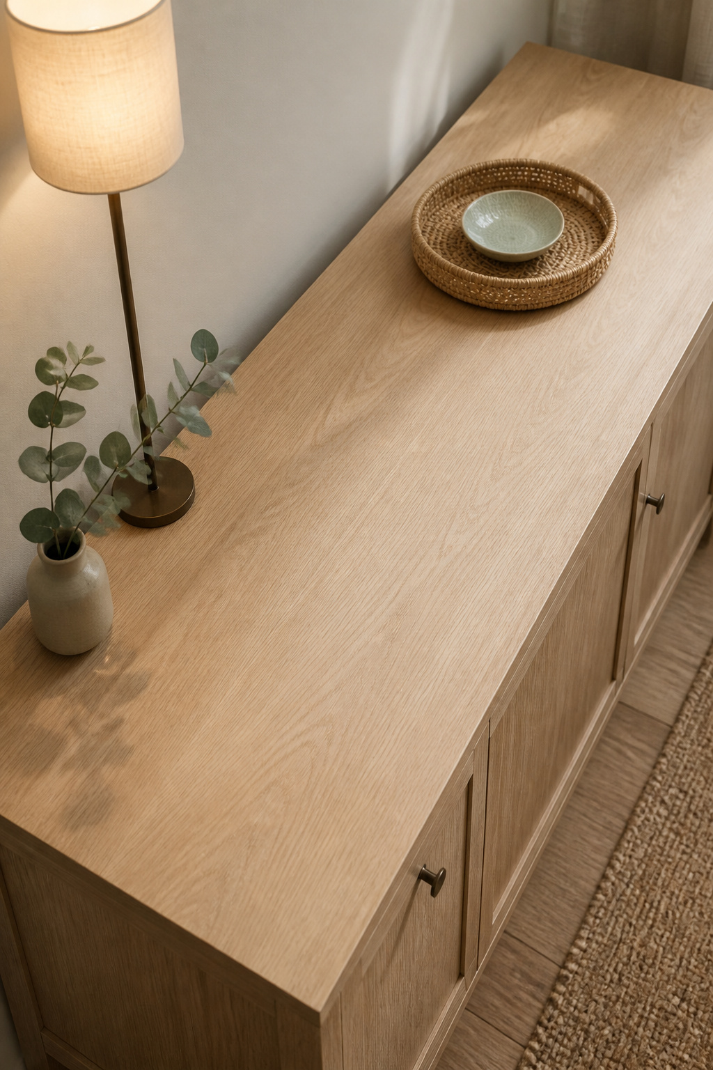 Overhead view of narrow oak sideboard with three objects — lamp, tray with bowl, eucalyptus stem — and clear centre serving zone