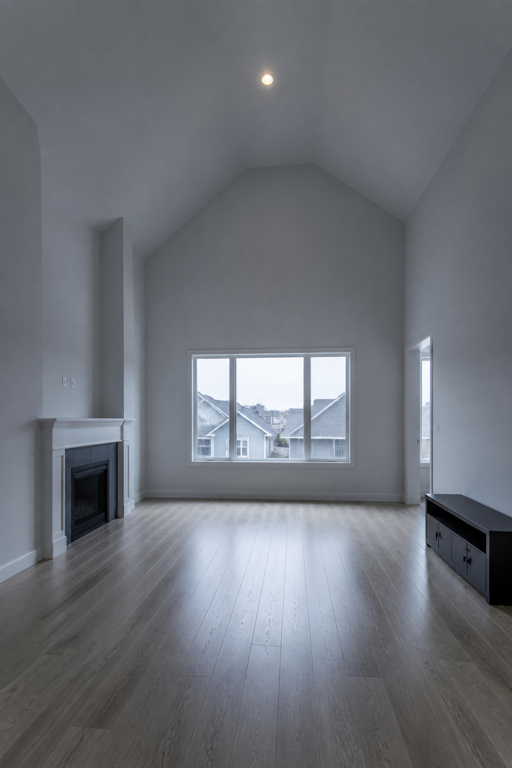 Empty vaulted ceiling living room with single overhead light and no textiles, illustrating the cold cavernous problem the article solves