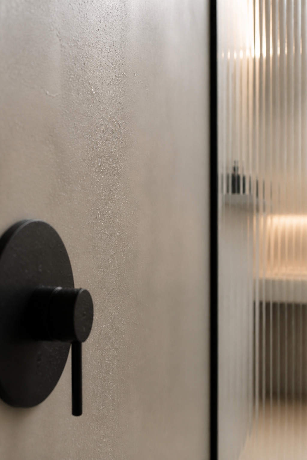 Sealed pale greige microcement wall with beads of water resting on the surface