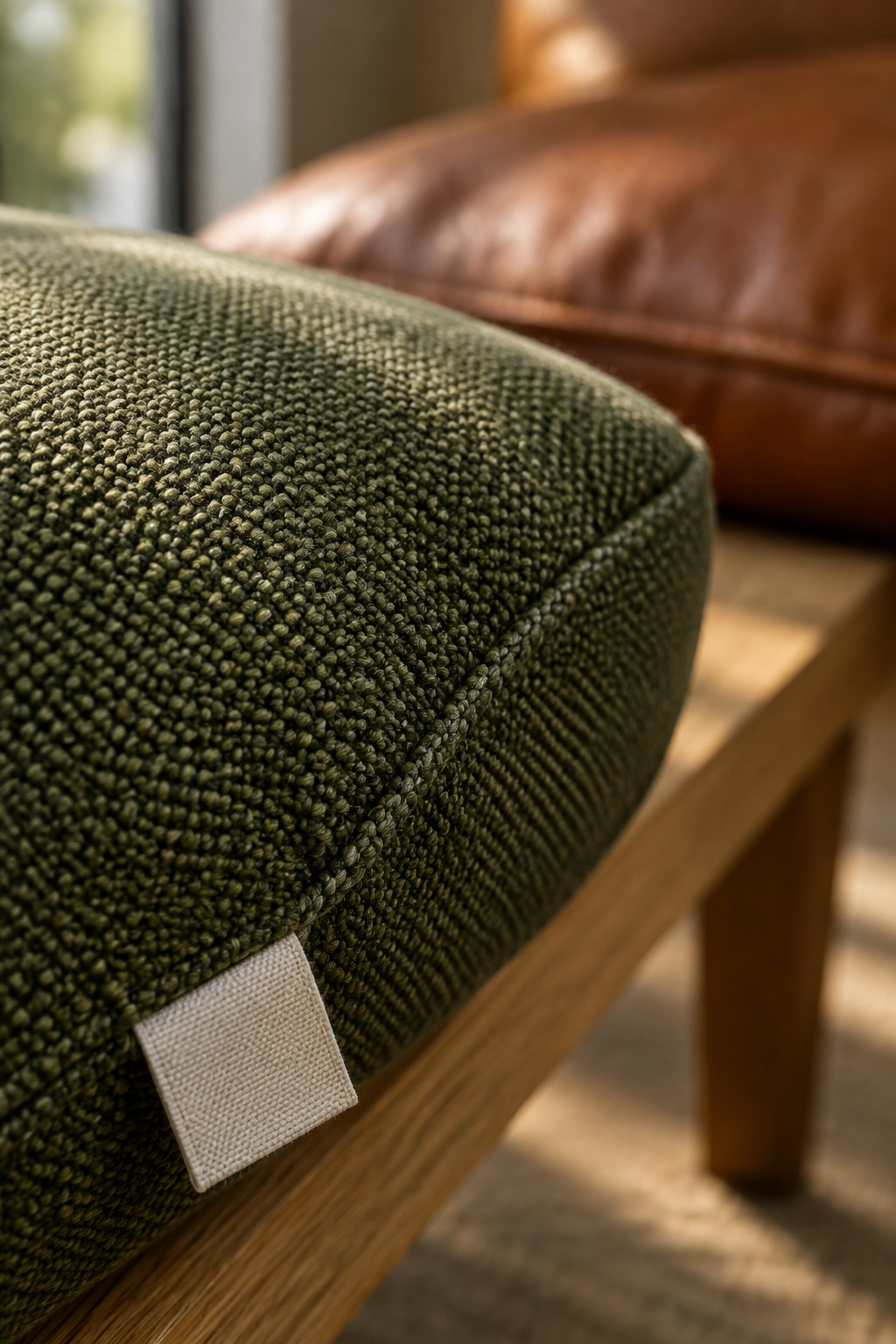 Raking light across a tightly woven olive performance fabric on a banquette cushion, showing individual yarns