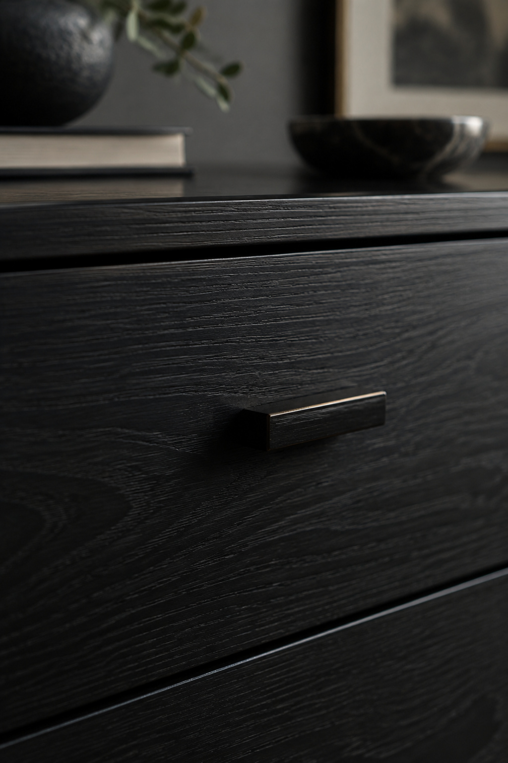 Close-up of a near-black ebonized wood drawer front with the natural grain still visible through the dark finish