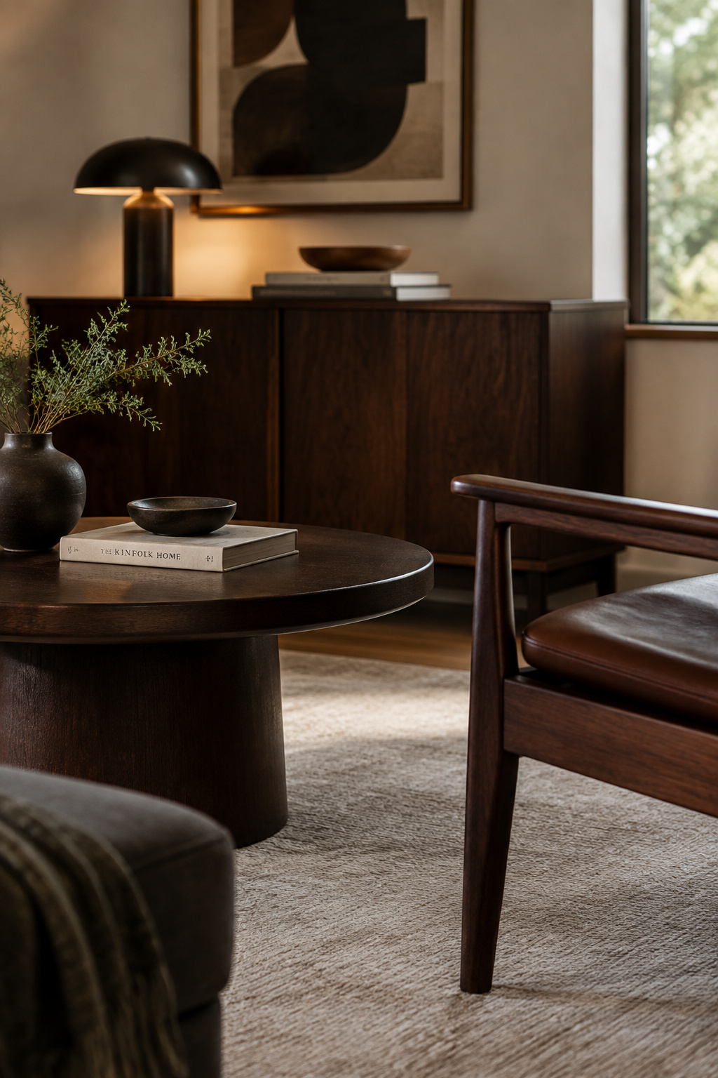 Three furniture pieces in complementary dark wood tones — a chest, a side table and a chair frame — grouped in a warm-lit room corner