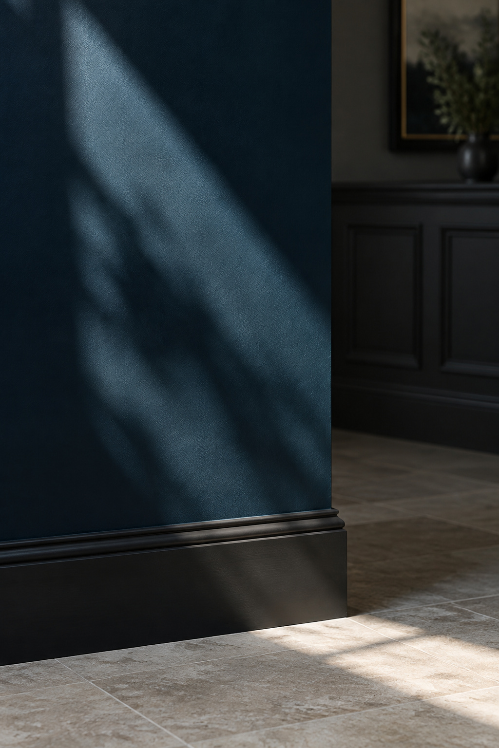 Deep navy entryway wall with a hard shaft of daylight crossing it, one side washed pale and one side near-black