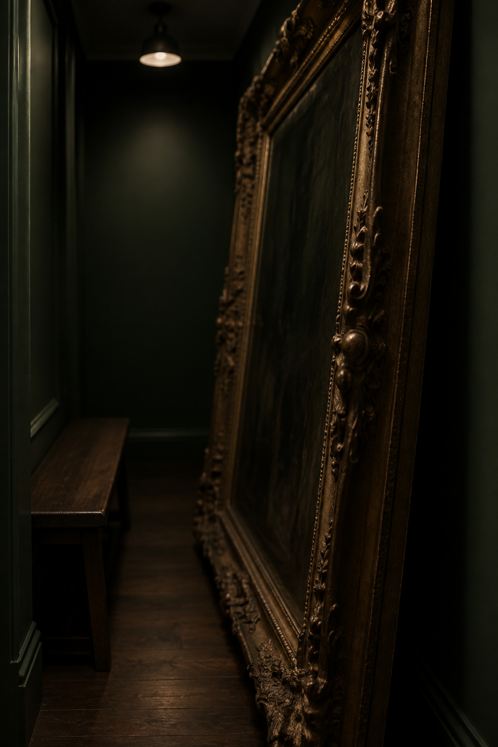 An oversized ornate frame crowding a narrow dark green entryway, mostly lost in shadow